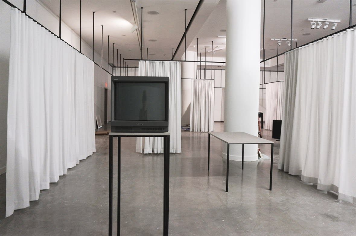 Exhibition installation featuring TV and tabletop surrounded by c