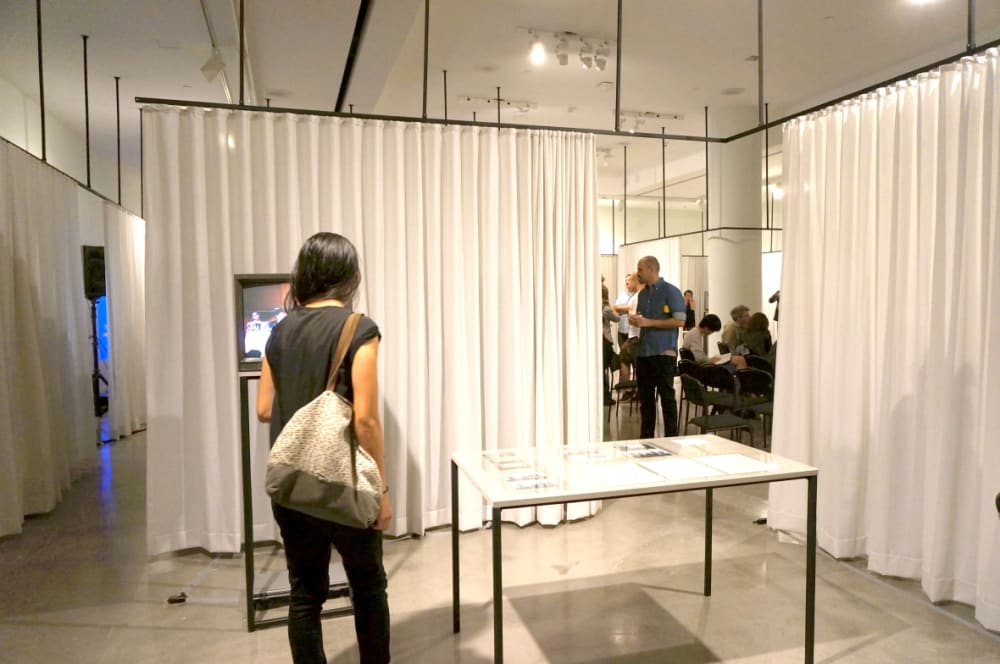 Exhibition installation featuring TV and tabletop surrounded by c