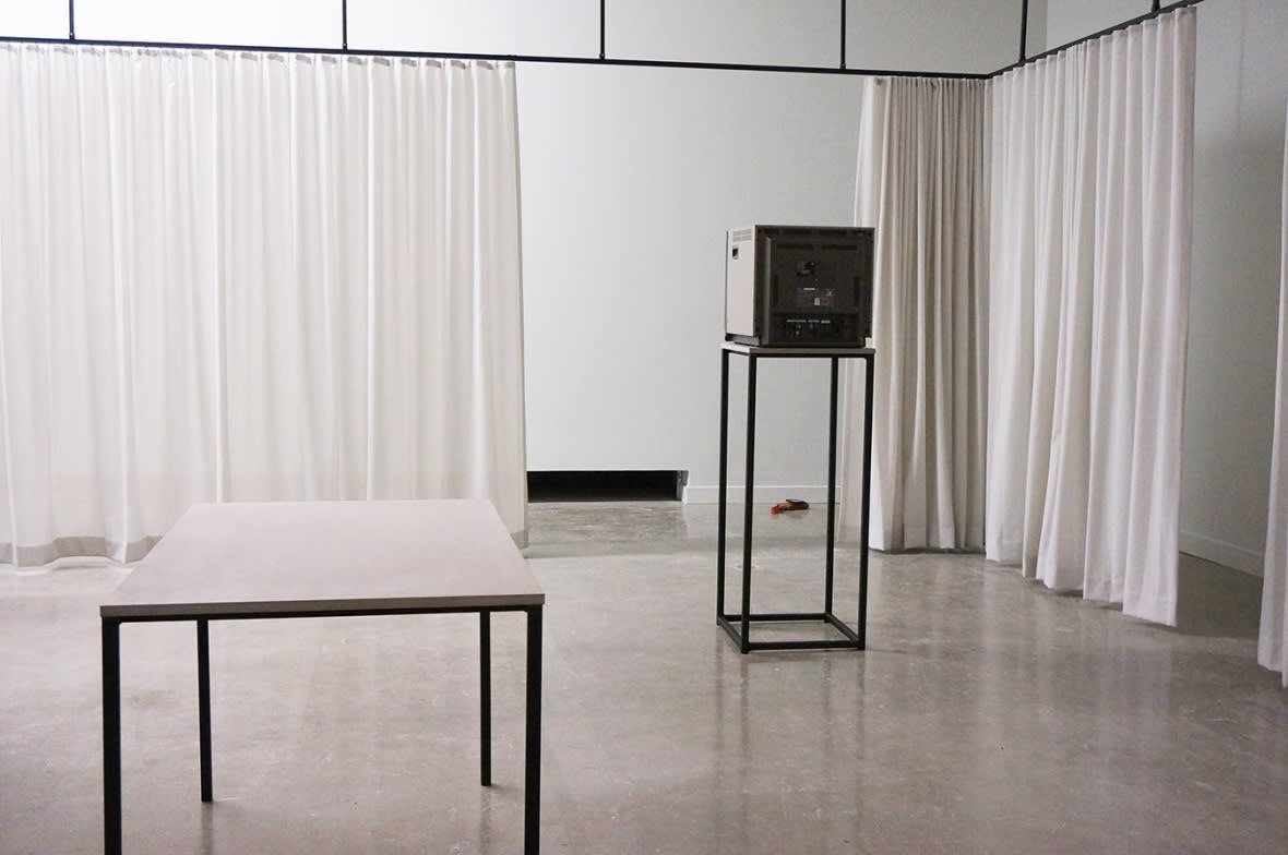 Exhibition installation featuring TV and tabletop surrounded by c